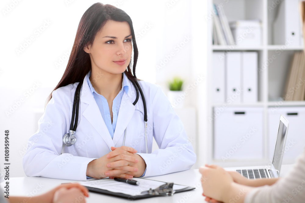 Brunette female doctor talking to patient in the hospital Brunette female doctor talking to patient in the hospital