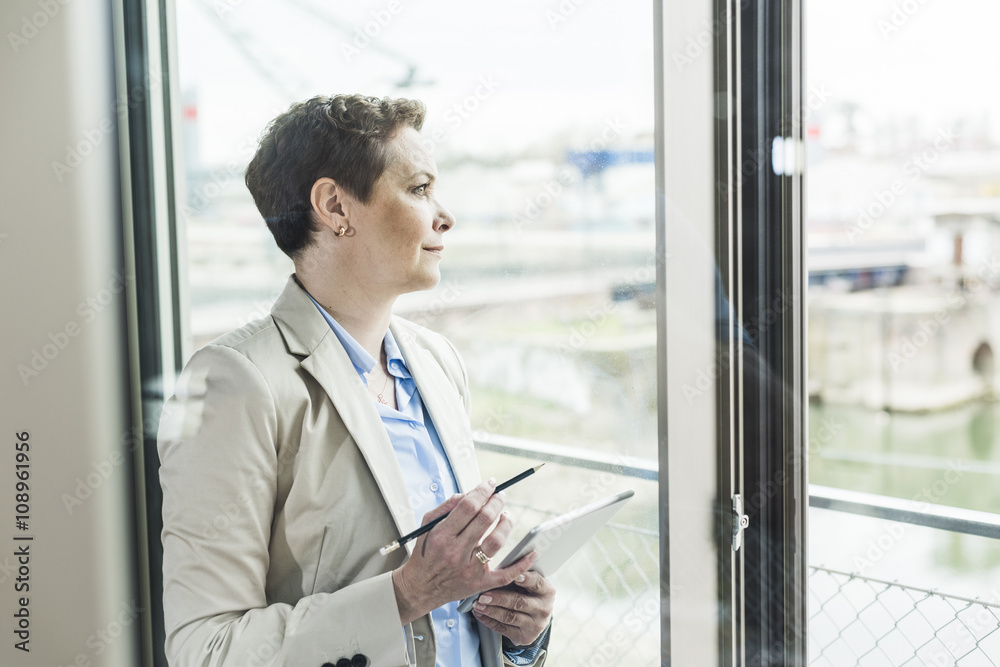 Businesswoman with digital tablet at the window Businesswoman with digital tablet at the window