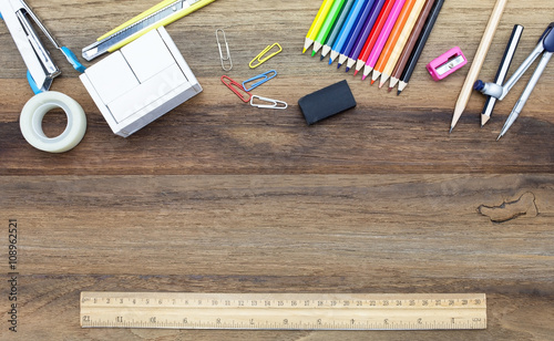 Business concept:stapler,glue,scissor,cutter,tape,pen,pencil,clip,ruler,rubber, cutting mat,divider,sharpener,ruler,wooden block calendar and color pencil on wooden