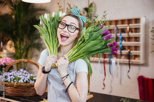 Funny happy woman florist holding two bunches of tulips photo