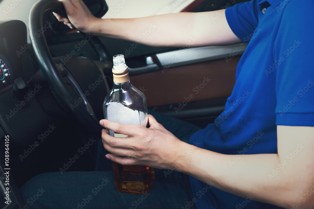 Man holding a bottle of liquor while driving in vintage tone