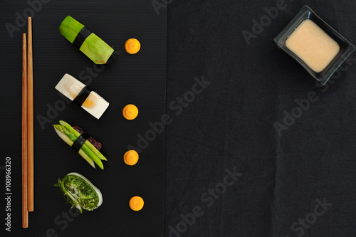 Obraz na płótnie Vegan Sushi with brown wild rice on black plate on black table. Top view. w salonie