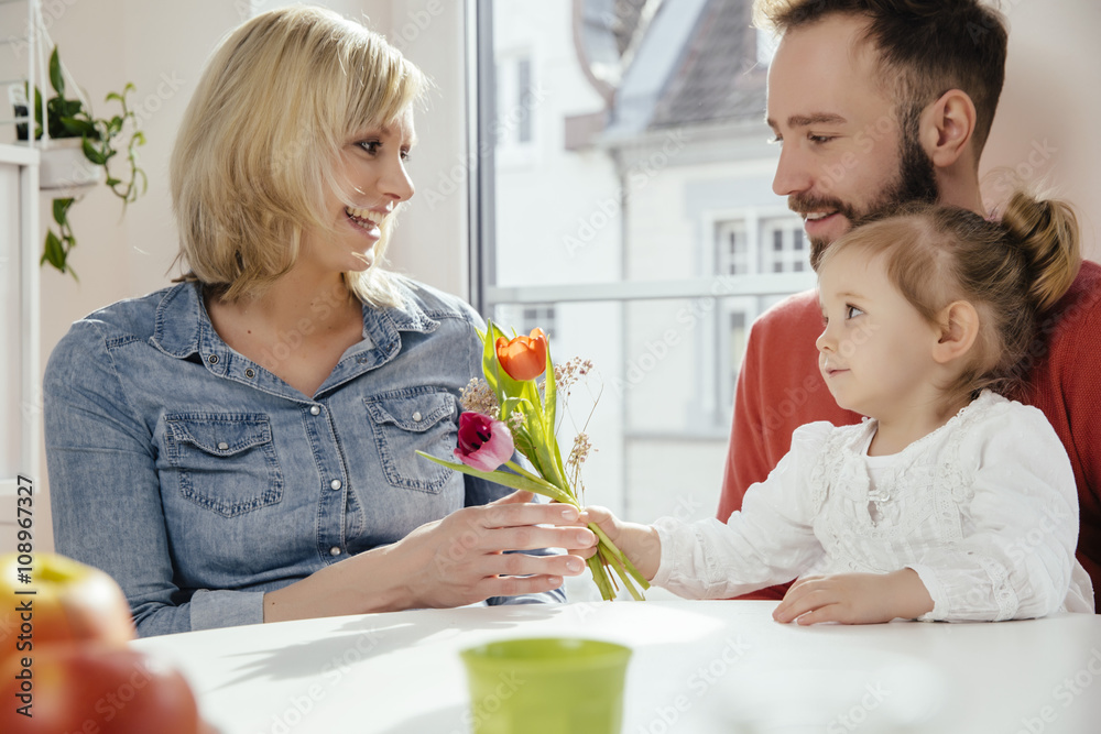 Little girl giving her mother flowers while father is watching Little girl giving her mother flowers while father is watching