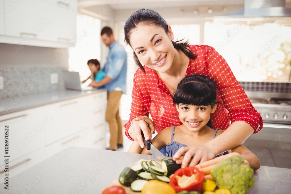 Portrait of happy mother teaching daughter to cut vegetables Portrait of happy mother teaching daughter to cut vegetables
