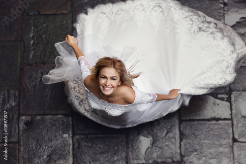 Romantic blonde bride posing in italian column street, from above