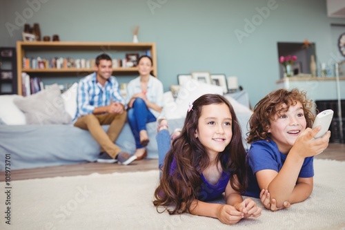 Happy children with remote while parents in background