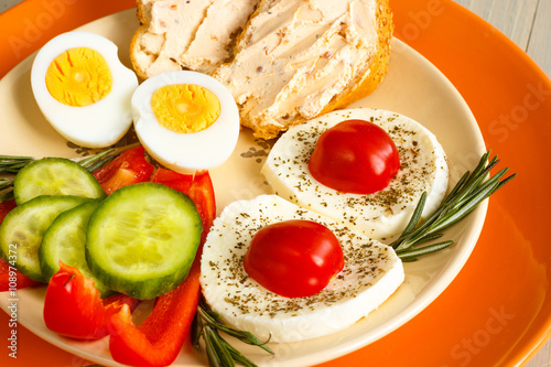 Healthy breakfast with eggs, cheese mozzarela, bread, rosrmary and fresh vegetables