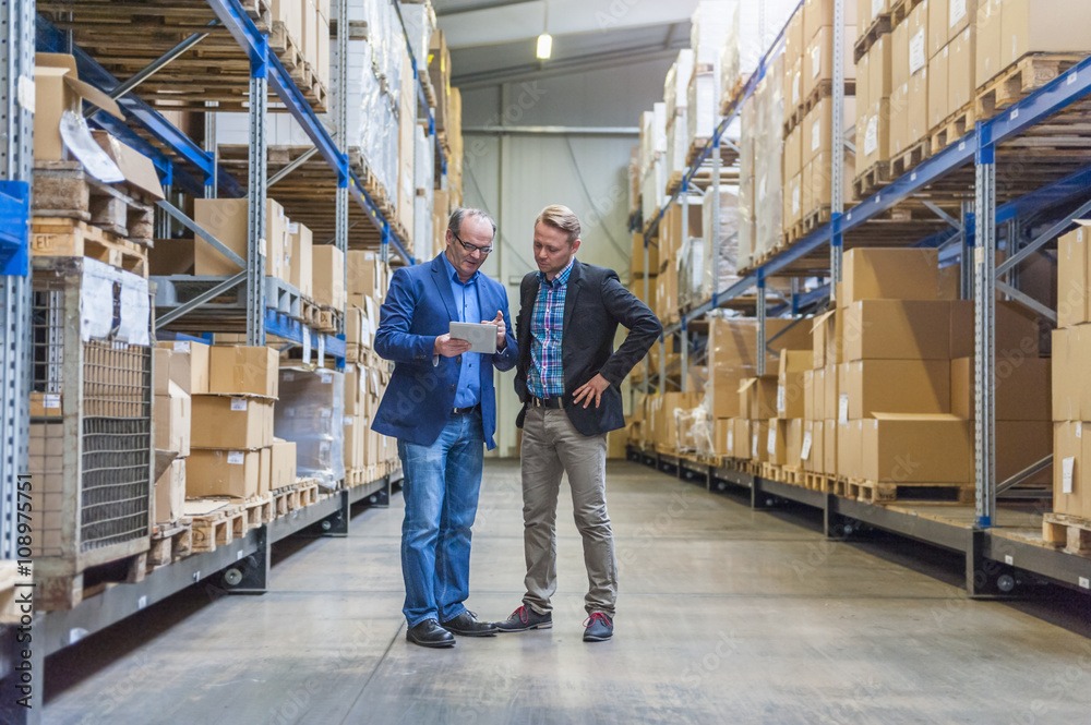 Two managers discussing packaging and shipment in storage hall Two managers discussing packaging and shipment in storage hall