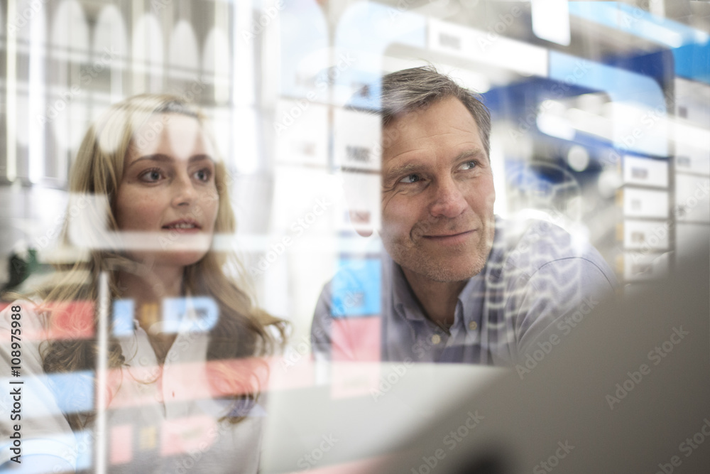 Man and woman looking at transparent touchscreen device Man and woman looking at transparent touchscreen device