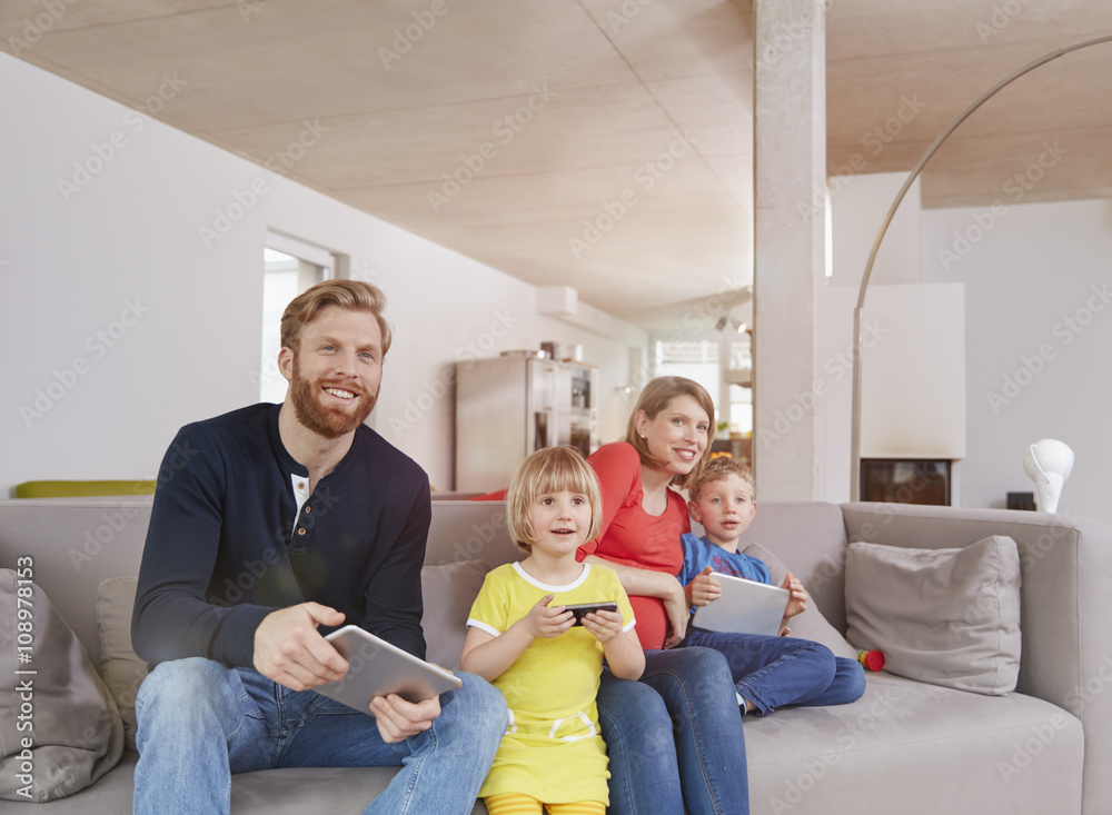 Family of four with mobile devices on couch Family of four with mobile devices on couch