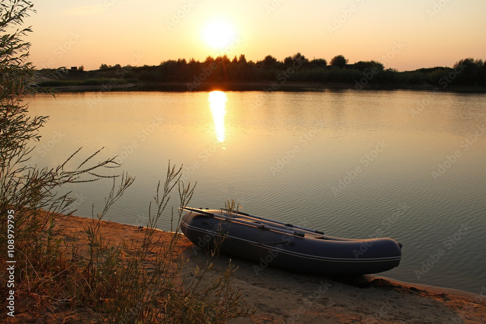 Sunset on the lake with a rubber boat on the shore.