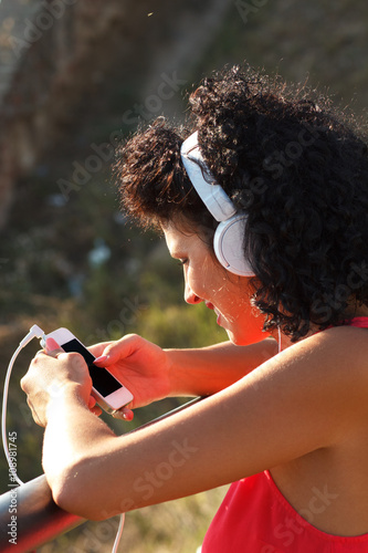 Portrait of young woman listening music on phone.