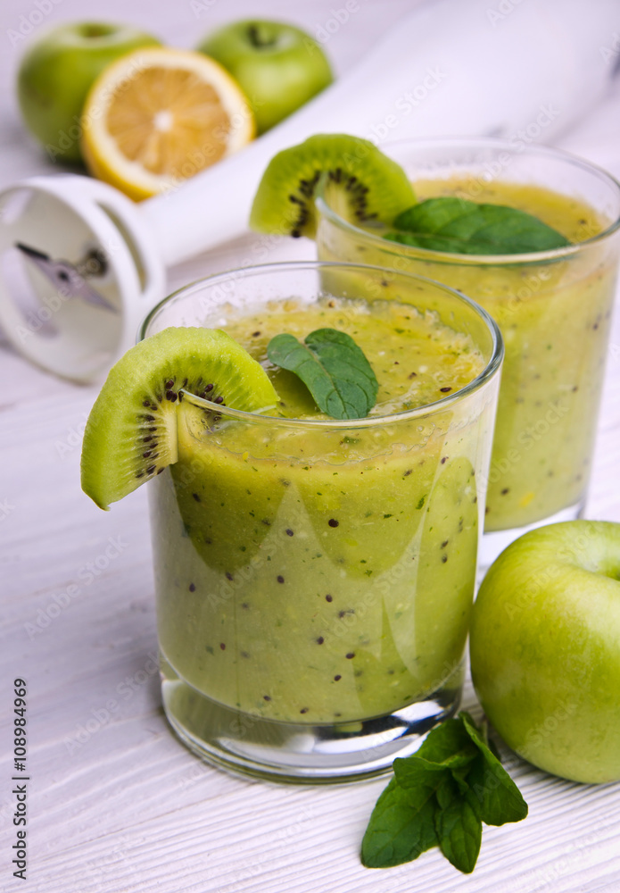 Green smoothie with mint and fruits on the wooden background Green smoothie with mint and fruits on the wooden background