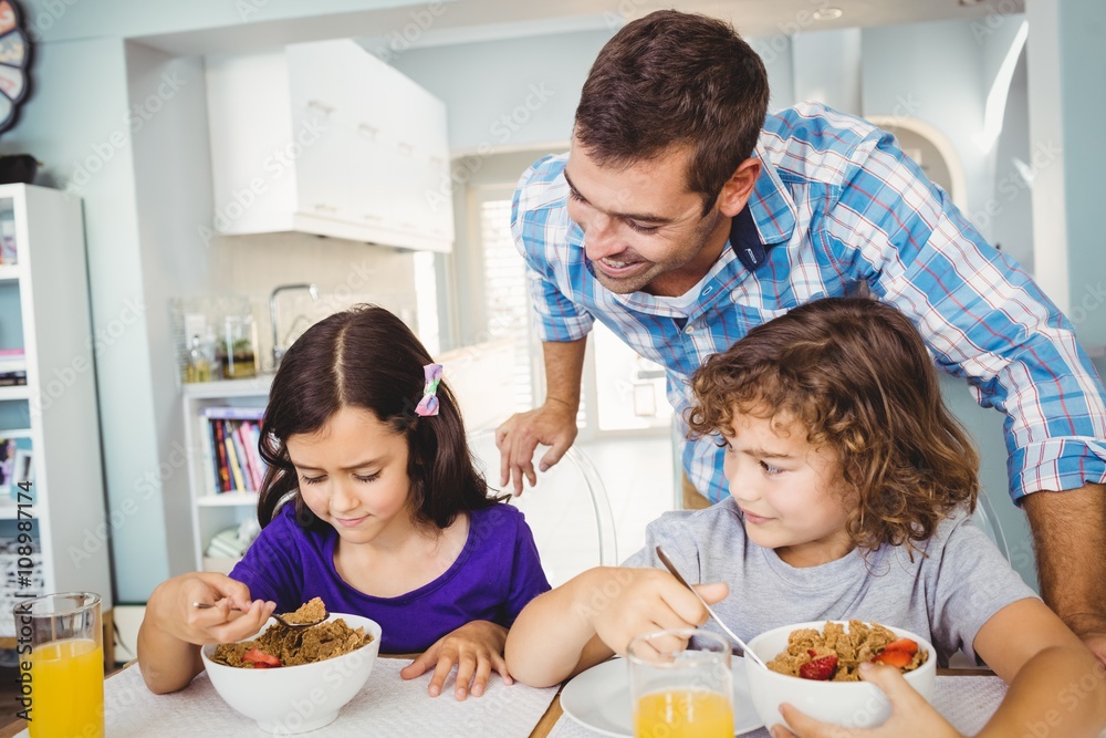 Cheerful man with children having breakfast at home Cheerful man with children having breakfast at home