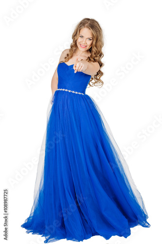 Studio shot young girl in elegant blue dress pointing finger at