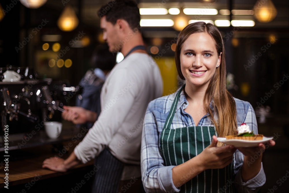 Pretty barista holding dessert and smiling at the camera Pretty barista holding dessert and smiling at the camera