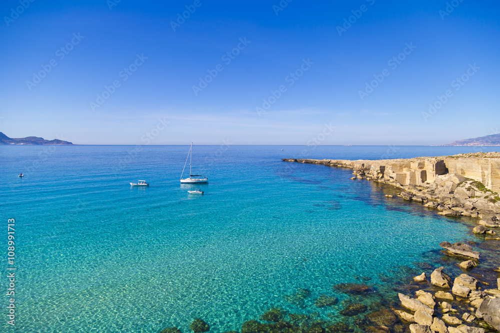 Azure lagoon called Cala Rossa with yachts moored on Favignana island in Sicily, Italy