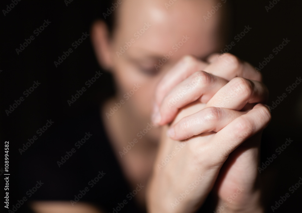 Portrait of young woman folding her hands in desperation. Praying concept. 