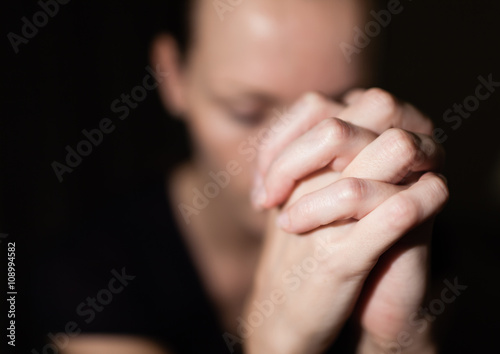 Portrait of young woman folding her hands in desperation. Praying concept. 
