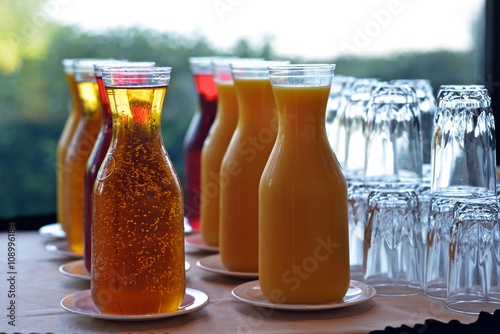 Carafes of various fruit juice and glasses photo