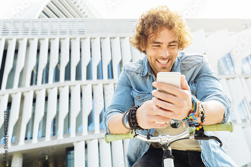 Portrait of Handsome young man smiling when he is using his mobi photo