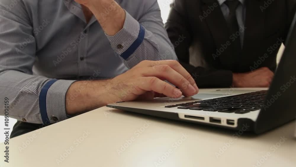 Two businessmen working in office, using laptop; handheld footage; Two businessmen working in office, using laptop; handheld footage;