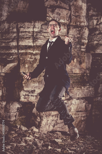 Emotional jumping businessman on the night rocks background.