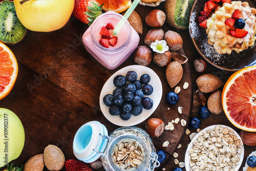 Health and colorful breakfast - with oat flakes, waffles, muffins,almond,hazelnuts,various fruits, berries and milk on old wooden table. Health food concept .Top view.