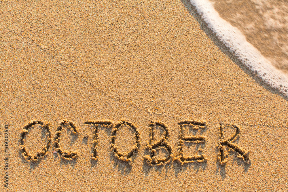 Fototapeta premium October - word drawn on the sand beach with the soft wave. Months series of 12 pictures.