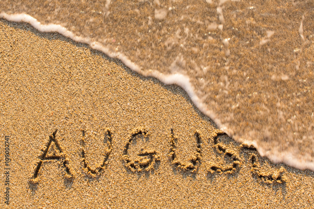 Fototapeta premium August - word drawn on the sand beach with the soft wave. Months series of 12 pictures.