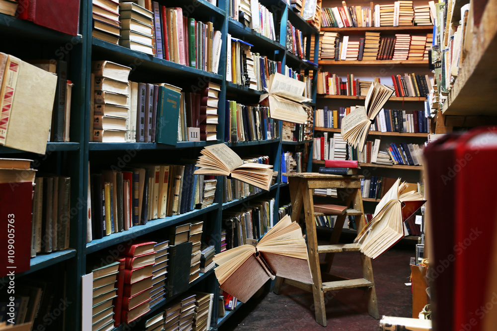 Flying books on library bookshelves background Flying books on library bookshelves background