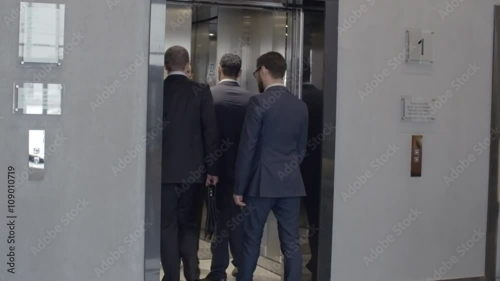 Group of business people waiting for elevator on the first floor, entering it and moving up Group of business people waiting for elevator on the first floor, entering it and moving up