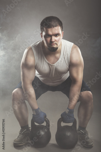Ыекщтп athlete дшаештп kettlebell. View from the front. Toned studio shot in a dark tone and smoke...