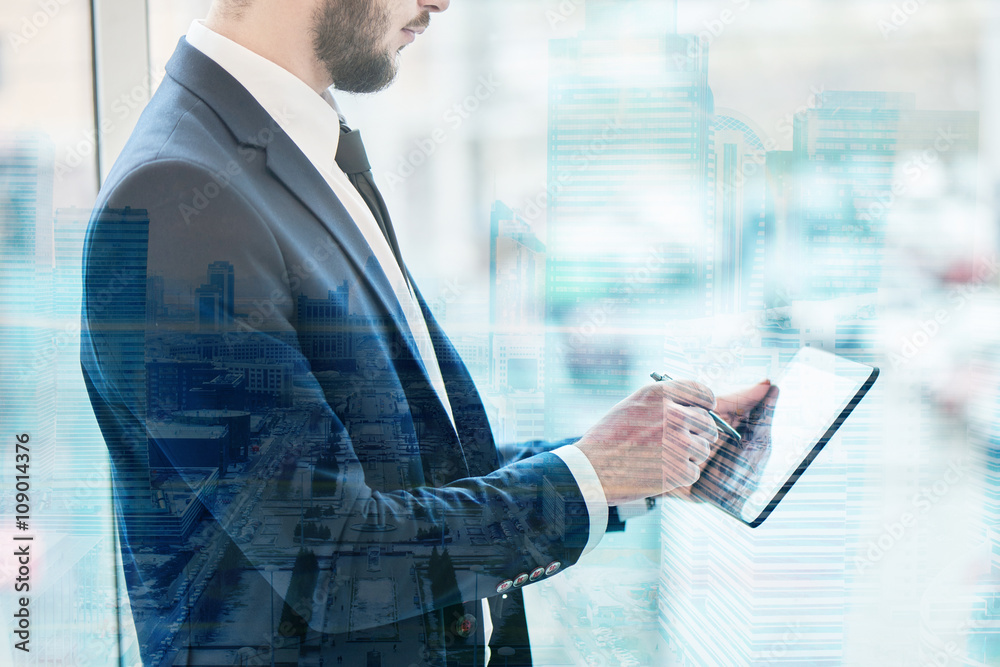 Tableau sur toile The guy's a businessman in a suit holding a tablet in hands