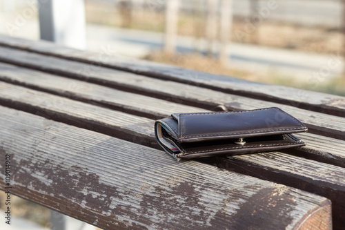 Lost brown leather wallet laying on bench