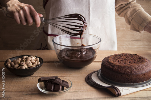 Woman cooking dark chocolate cake with ganache and pistachios