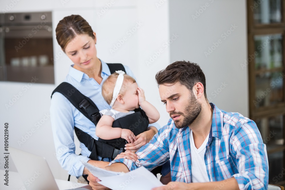 Man reading documents while wife carrying baby Man reading documents while wife carrying baby