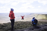 A group on top of a mountain, with a photographer and a girl jumping, Pen Y Fan