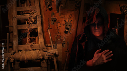 Medieval inquisitor in the hood on the inquisitors tools backgro photo
