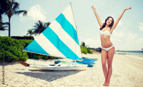 happy woman in bikini swimsuit dancing on beach