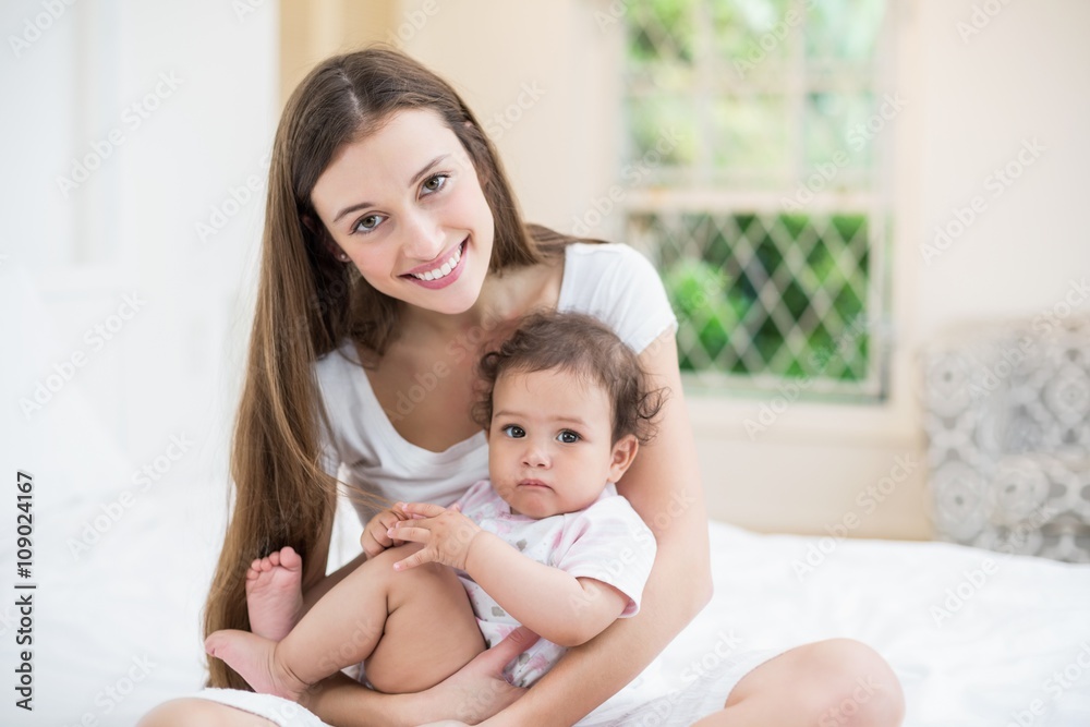 Smiling mother carrying daughter while sitting on bed at home Smiling mother carrying daughter while sitting on bed at home