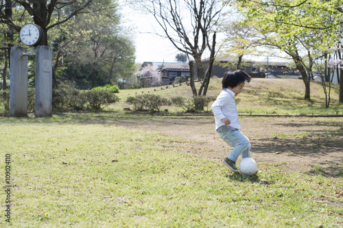 Young boy is chasing a ball in the park