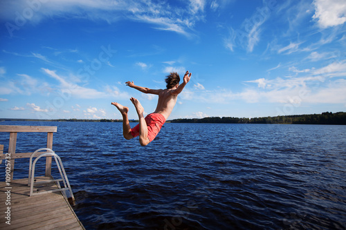 Valokuvatapetti Young man jumping into water