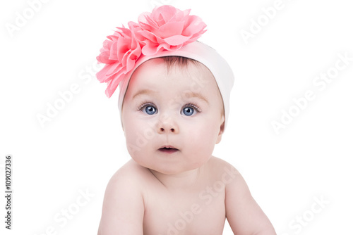 portrait of cute little baby girl with pink bow flower on her head. kid looks into the camera with admiration. child girl with big blue eyes. happy family concept