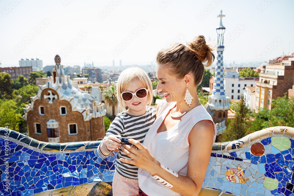 Fototapeta premium Szczęśliwa mama i dziecko sprawdzające zdjęcia w aparacie w Park Guell