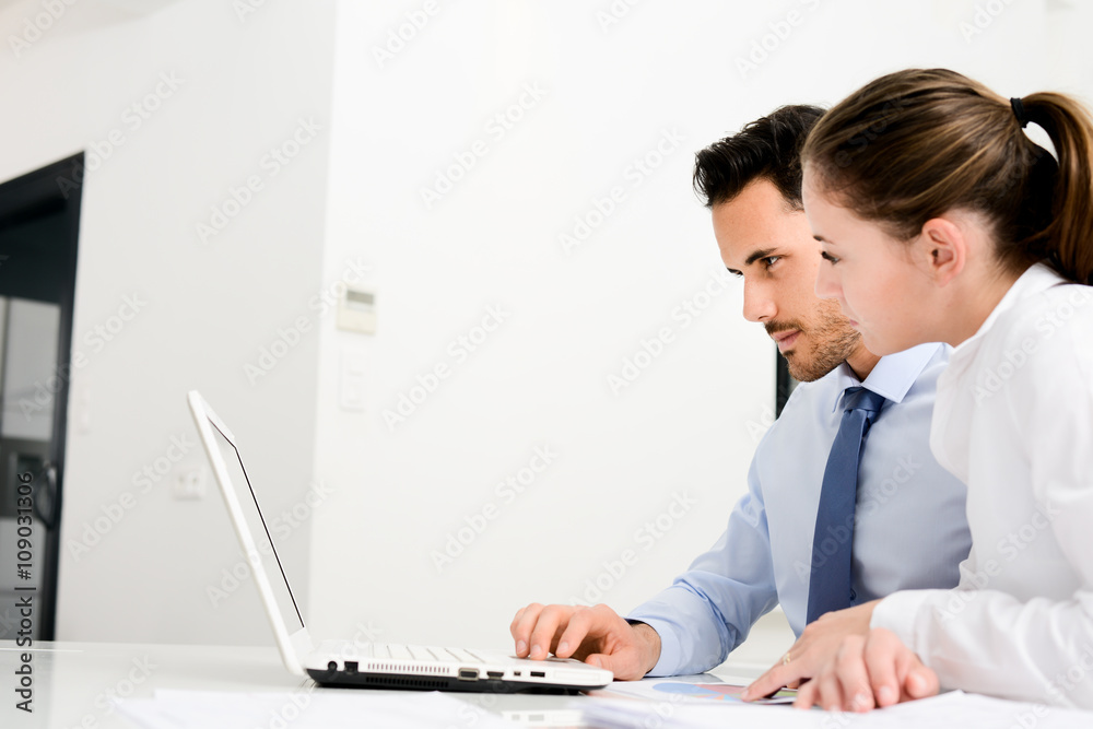 business people man and woman working together with a laptop computer in office business people man and woman working together with a laptop computer in office