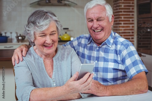 Loving senior couple using mobile phone