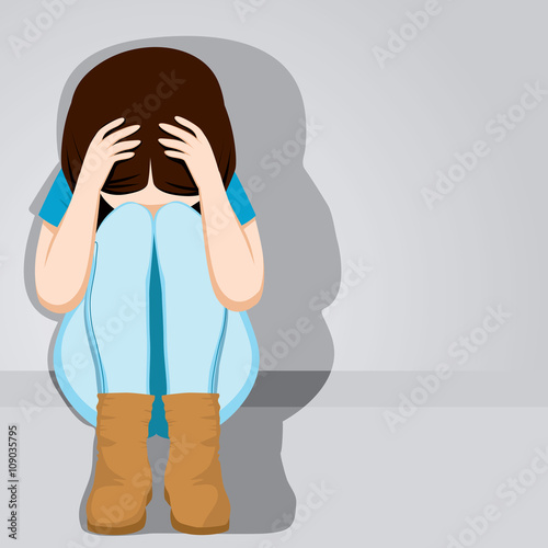 Sad teenager girl desperate hiding her face sitting on floor on grey background