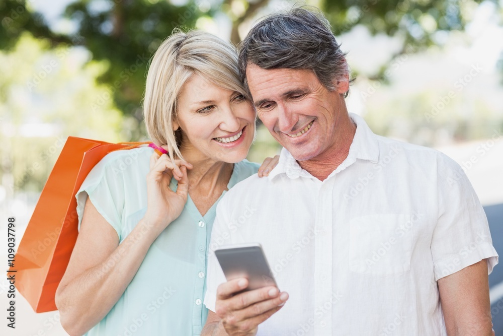 Couple using cellphone while smiling Couple using cellphone while smiling