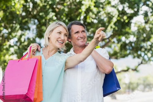 Woman pointing to happy man with shopping bags